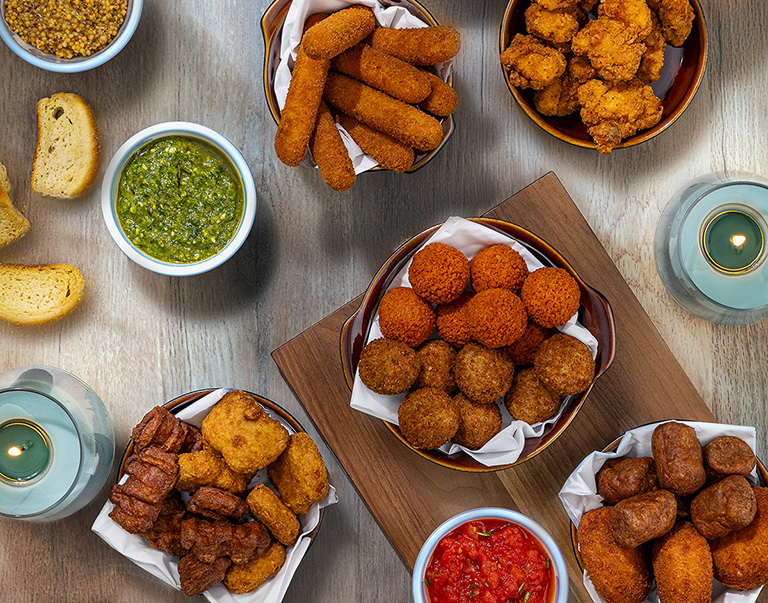 Un savoureux plateau de bouchées croustillantes, de bâtonnets de mozzarella et de croquettes variées, accompagnés de dips maison. 