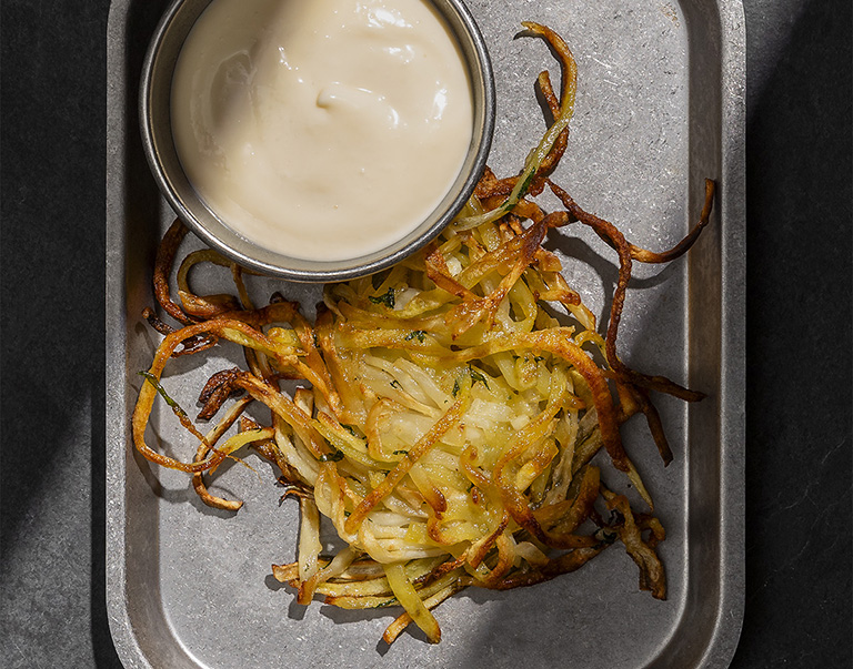 Rösti de céleri-rave croustillants avec pommes de terre, ail, zeste de citron et feuilles de céleri. Une délicieuse adaptation d'un plat classique.