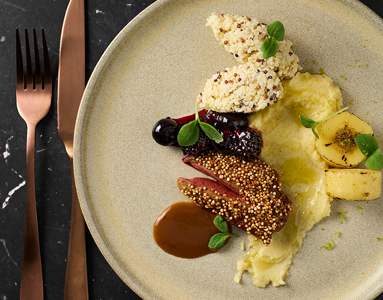 Un plat raffiné composé de filet de pigeon d’Anjou au quinoa croustillant, de deux préparations de panais, d’un coulis de myrtille frais et d’un riche jus de 